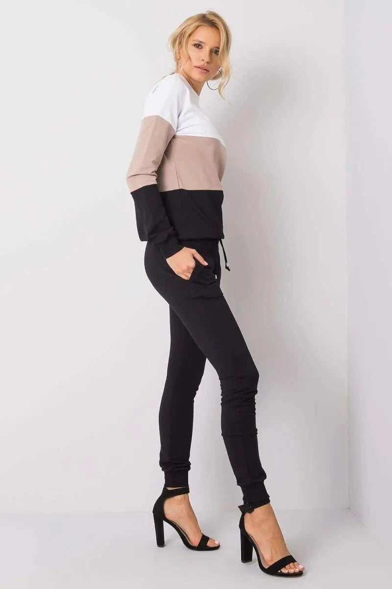 Woman in a colorblock sweatshirt and black joggers, wearing black strappy heels.