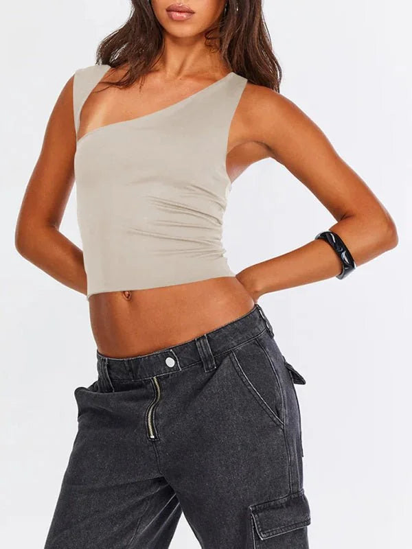 Tan one-shoulder crop top with a ribbed texture, paired with dark wash cargo pants.