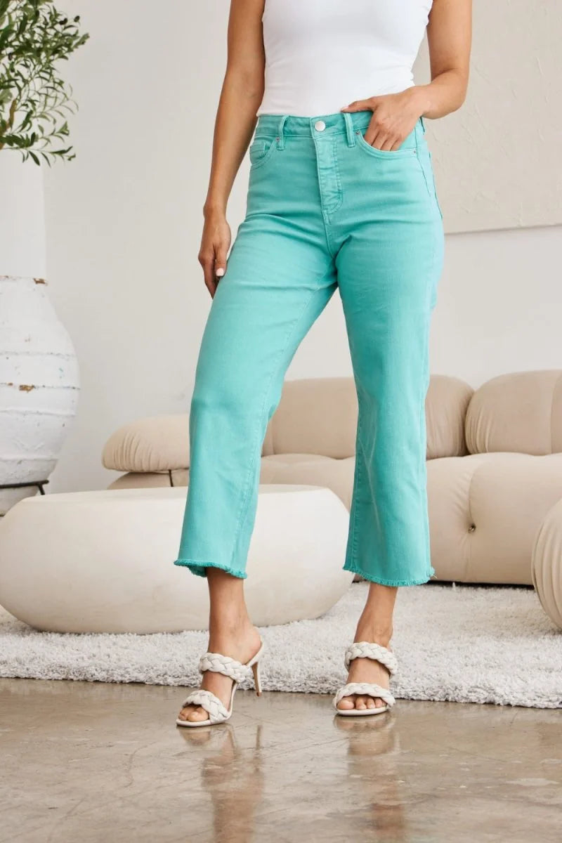 Turquoise cropped jeans with frayed hem and moderate stretch, on a model.