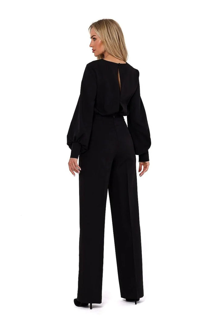 Back view of a woman wearing a black jumpsuit with voluminous sleeves and wide-leg pants.