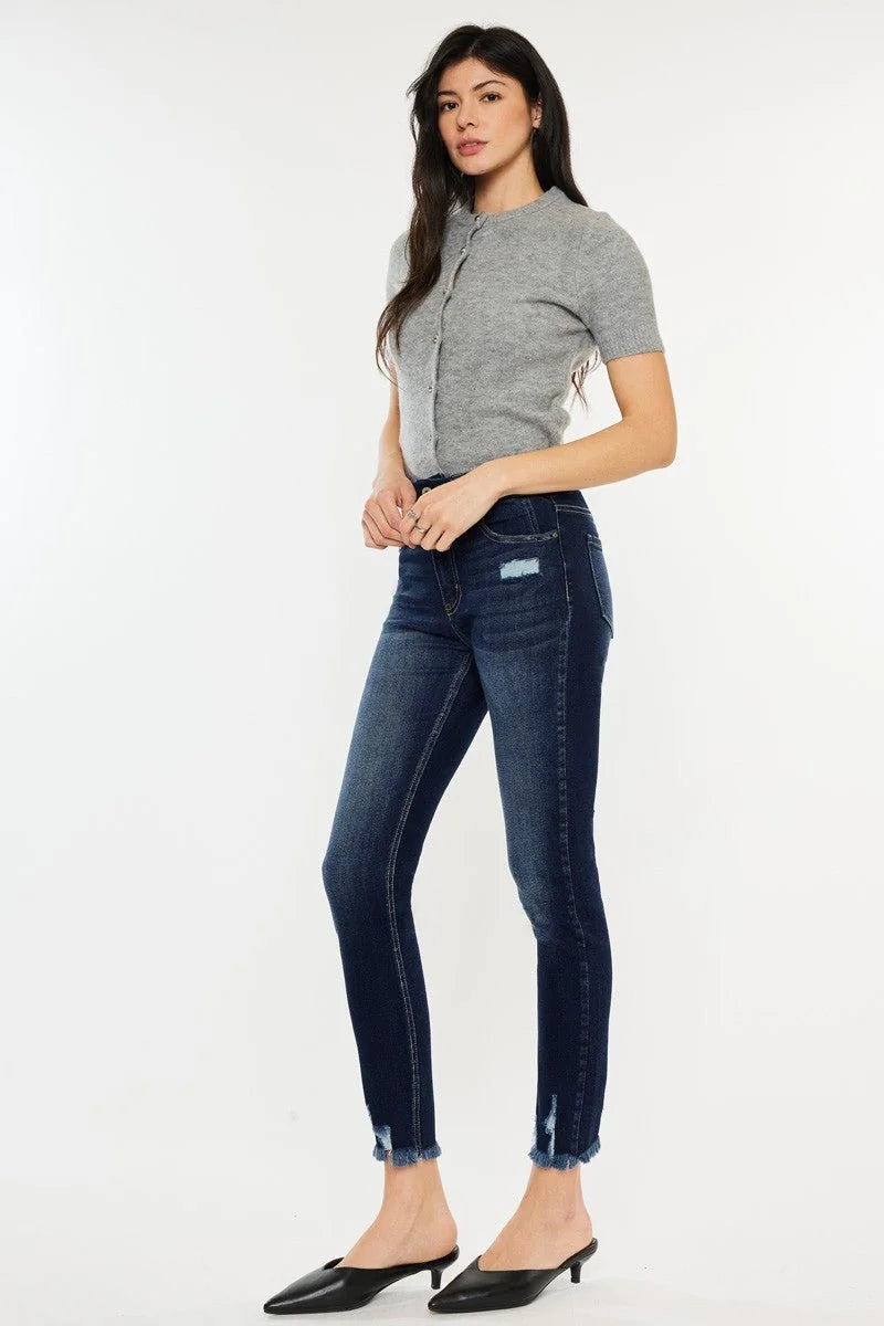 Dark wash denim jeans with frayed hem and distressed detail on model.