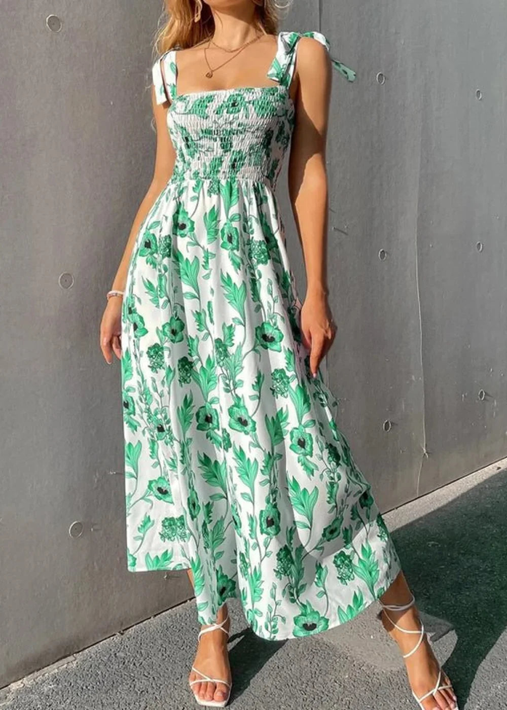 White maxi dress with green floral print, smocked bodice, and tie straps on model.