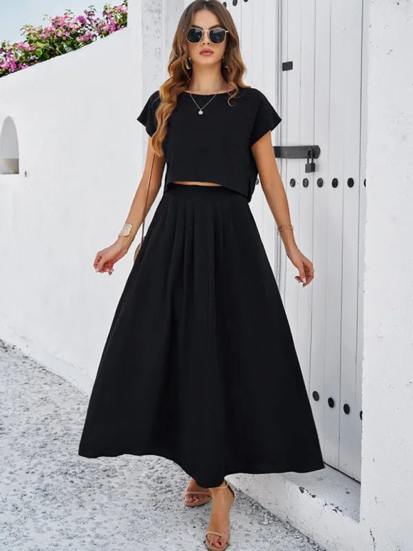 Black viscose two-piece set with cropped top and pleated midi skirt on a model.
