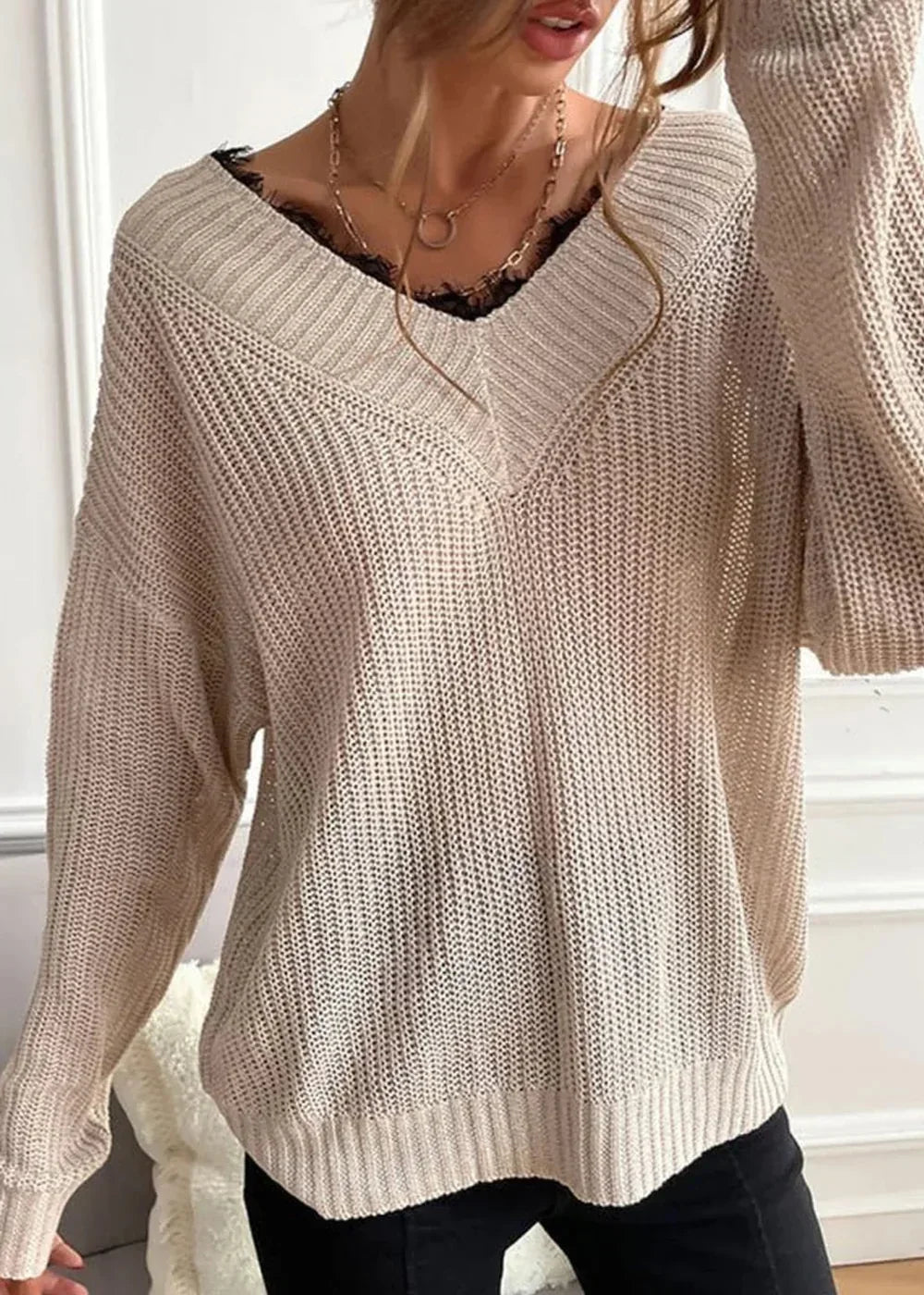 Beige knit v-neck sweater with black lace trim and layered necklaces.