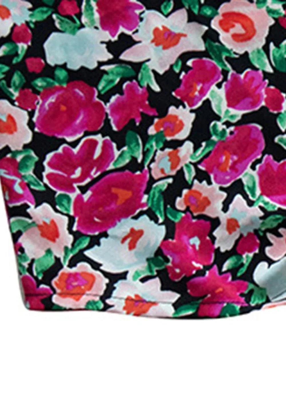 Close-up of a black fabric with a vibrant floral print featuring fuchsia, pink, white, and orange flowers with green leaves.