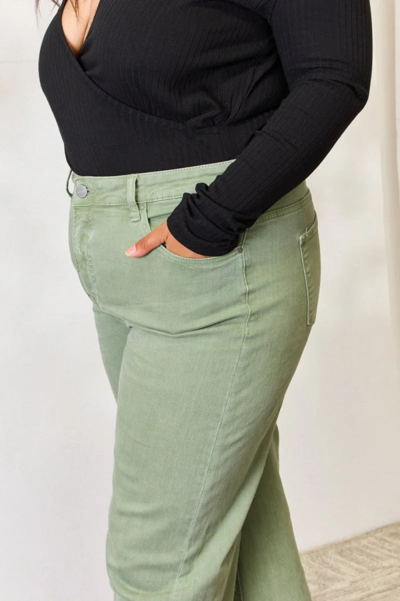 Close-up of light green high-waisted pants with a black ribbed top, showing pocket detail.