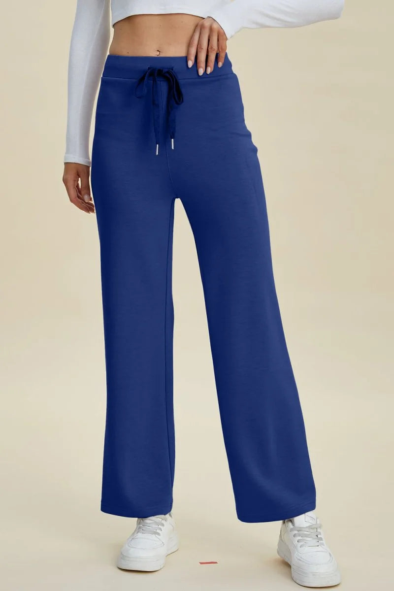 Navy blue wide-leg sweatpants with drawstring waist and white sneakers.