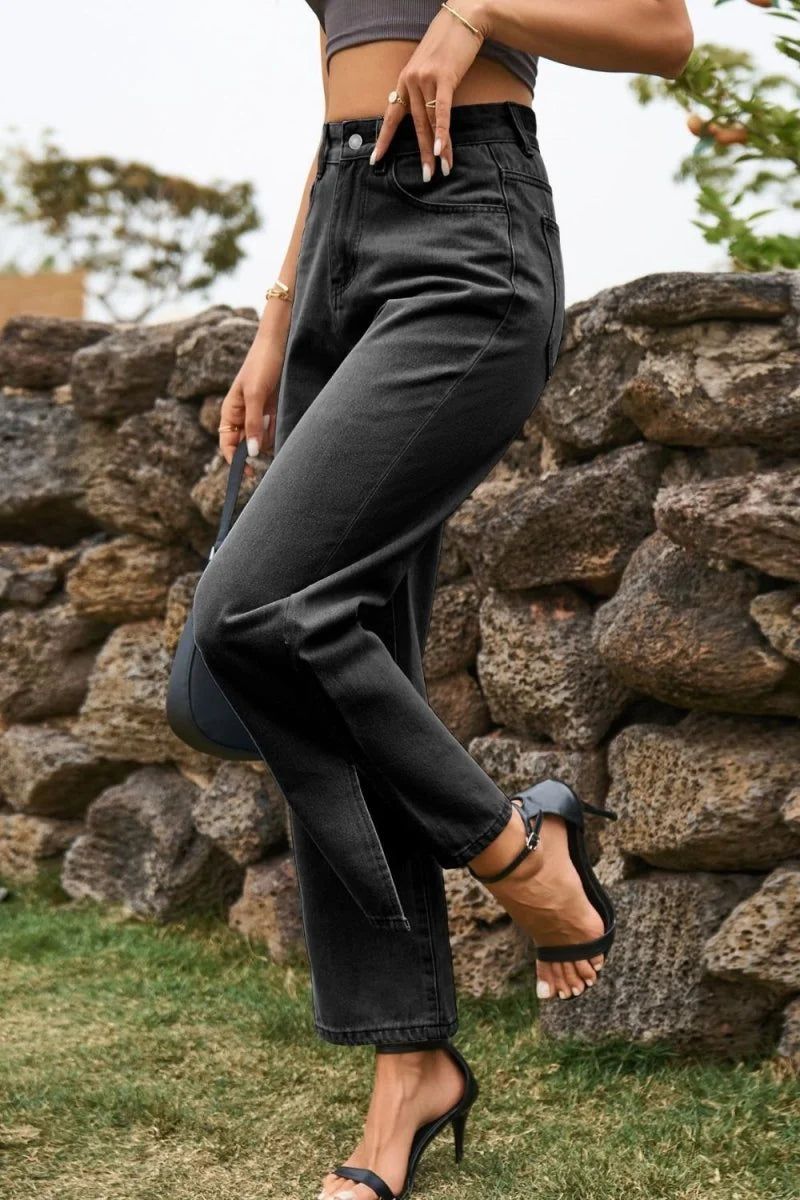 Close-up of black denim jeans with a high waist, worn by a model with black heeled sandals.