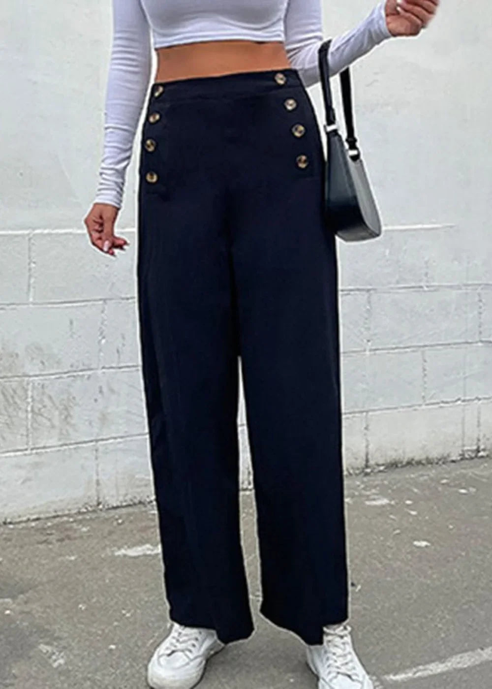 Navy blue wide-leg pants with gold button details and a white long-sleeve top.