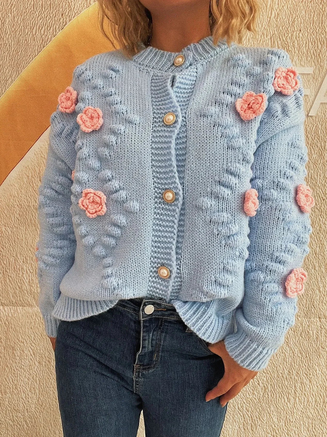 Light blue knit cardigan with pink floral appliques and pearl buttons.