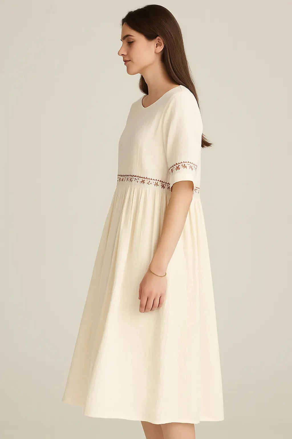 Cream linen-blend midi dress with embroidered details on the bodice and sleeves, on a model.