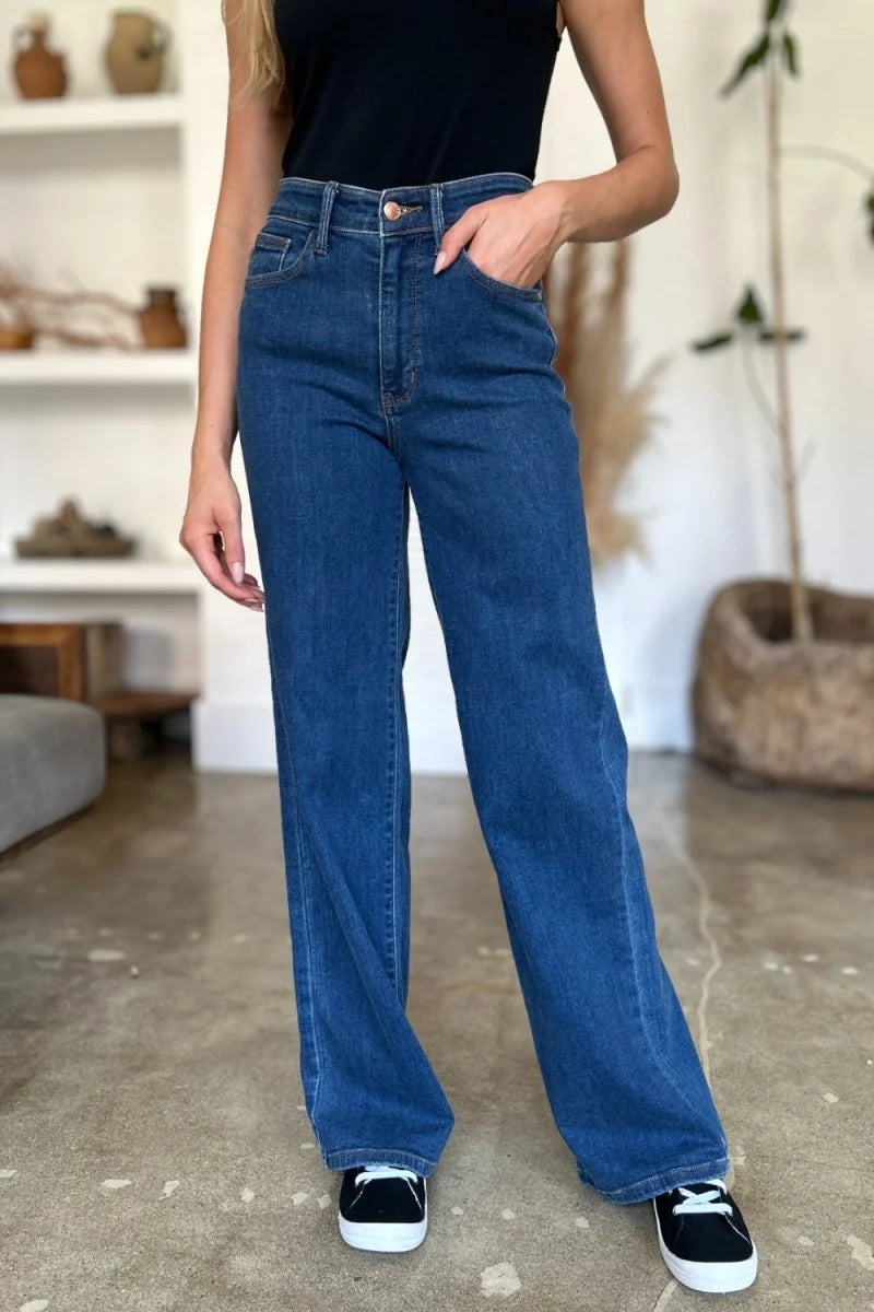 Dark wash wide-leg denim jeans with a classic five-pocket design and a button-zip fly, shown on a model.