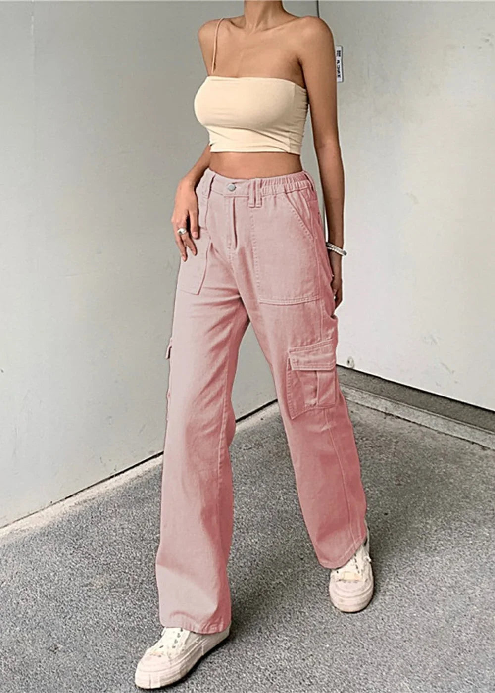 Pink cargo pants with a relaxed fit and visible pocket details, paired with white sneakers on a model.