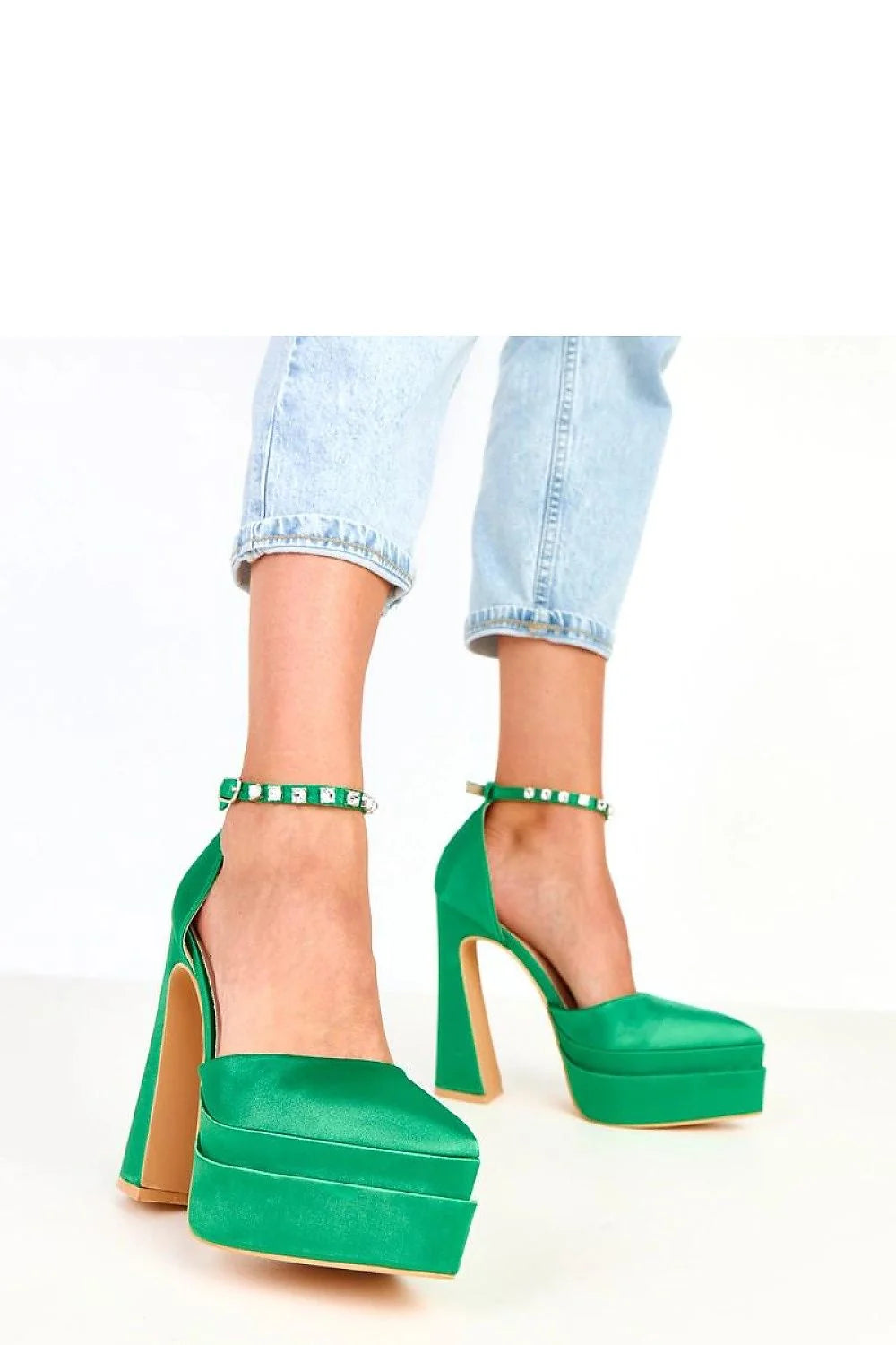 Emerald green satin platform heels with jeweled ankle straps on a model.