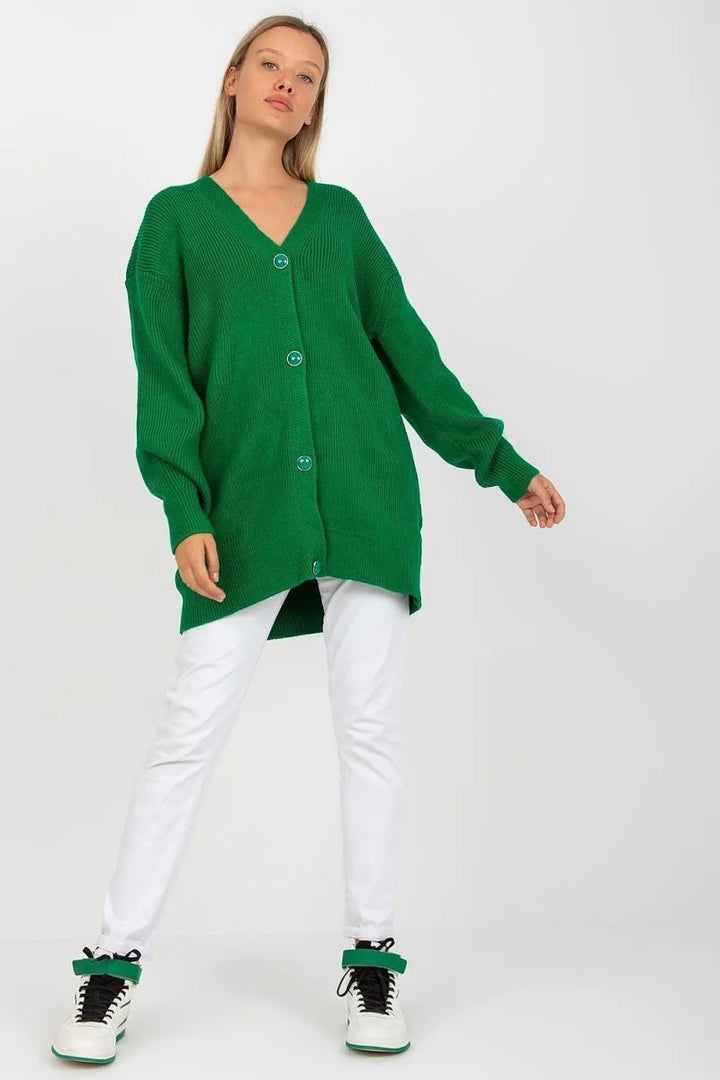 Woman in green long cardigan and white pants, with green and white high-top sneakers.