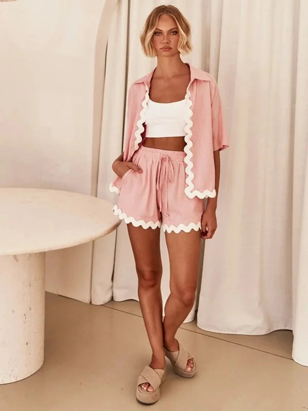Pink scalloped short suit with white crop top and tan platform sandals on model.