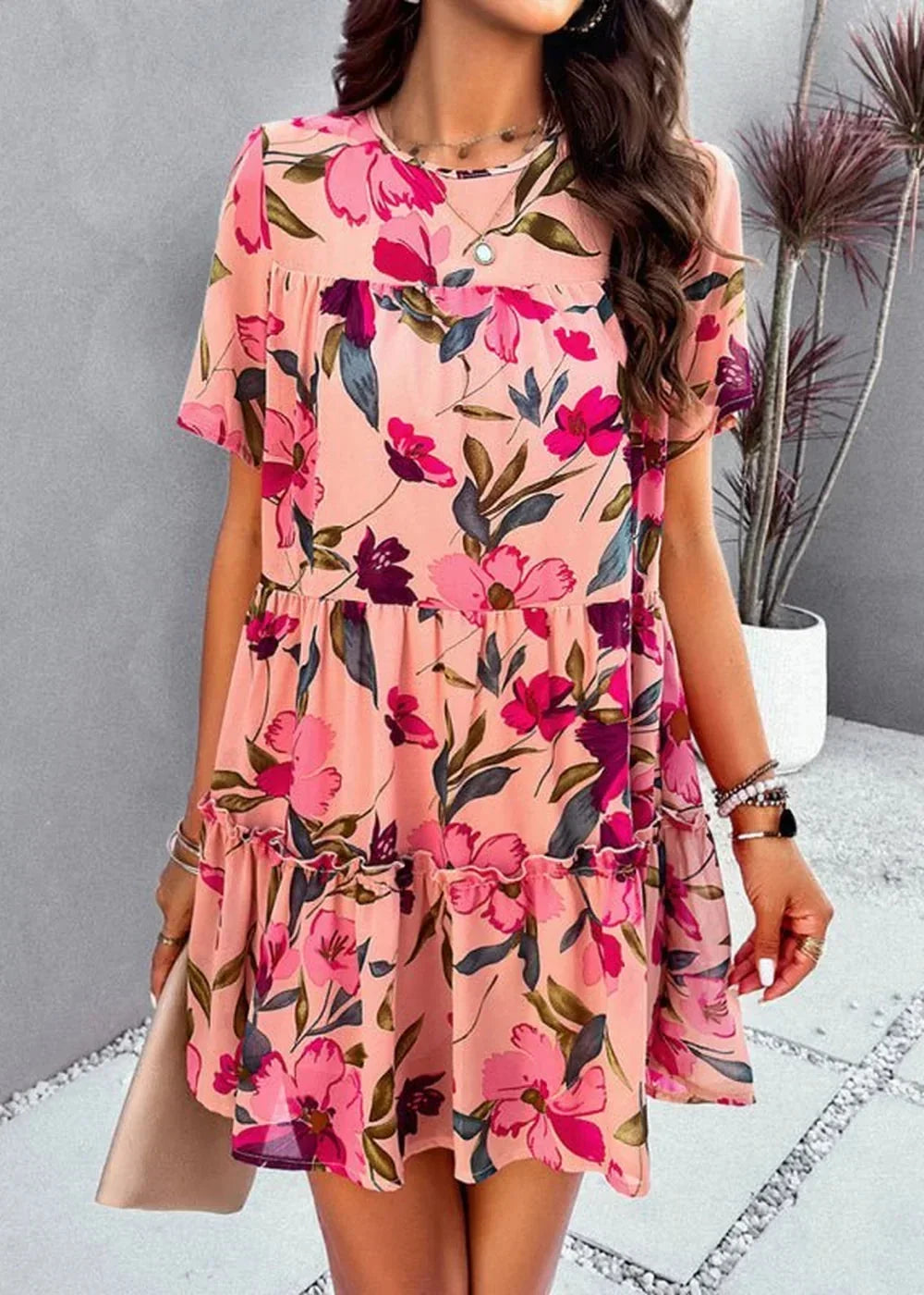 Pink floral print polyester dress with ruffled tiers and short sleeves, on model.