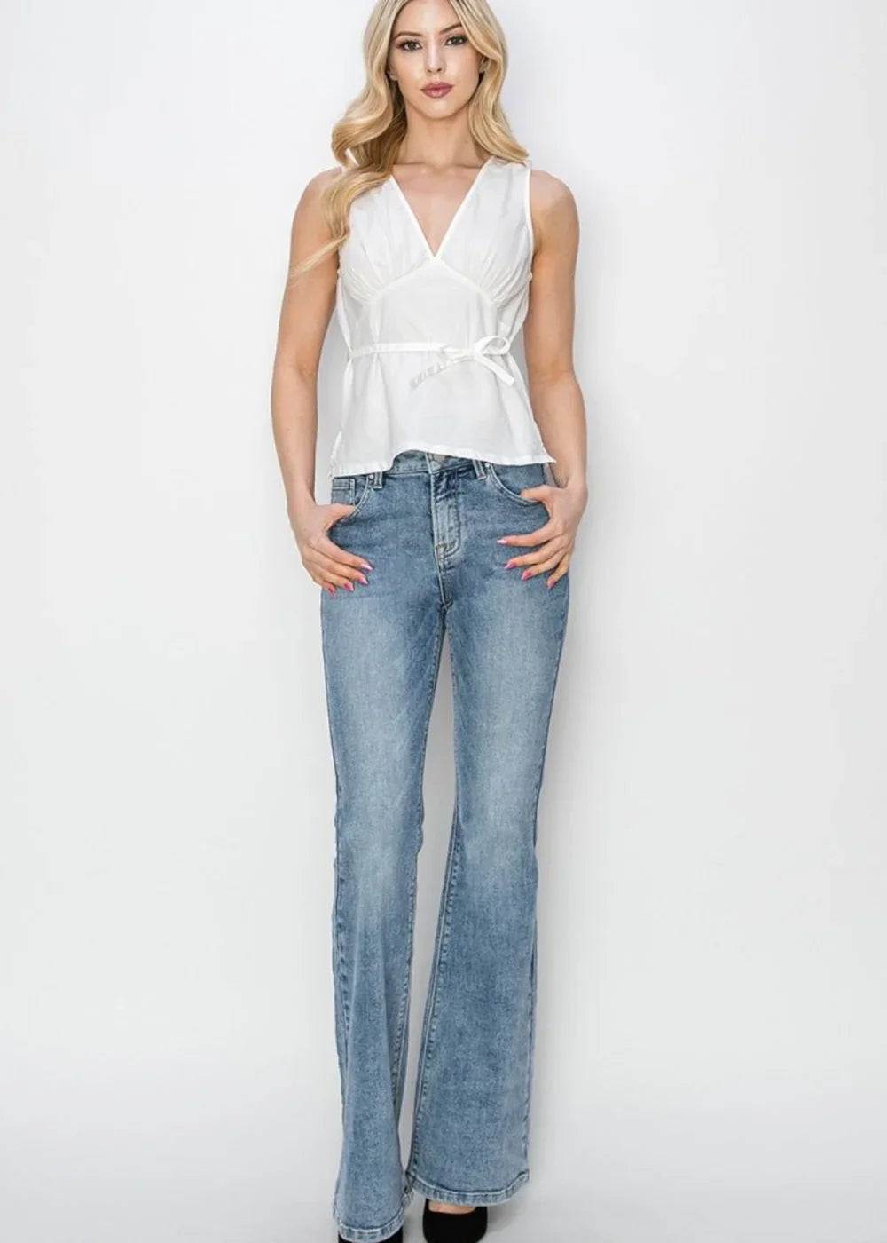 Light wash, flared denim jeans with a distressed texture, worn by a model.