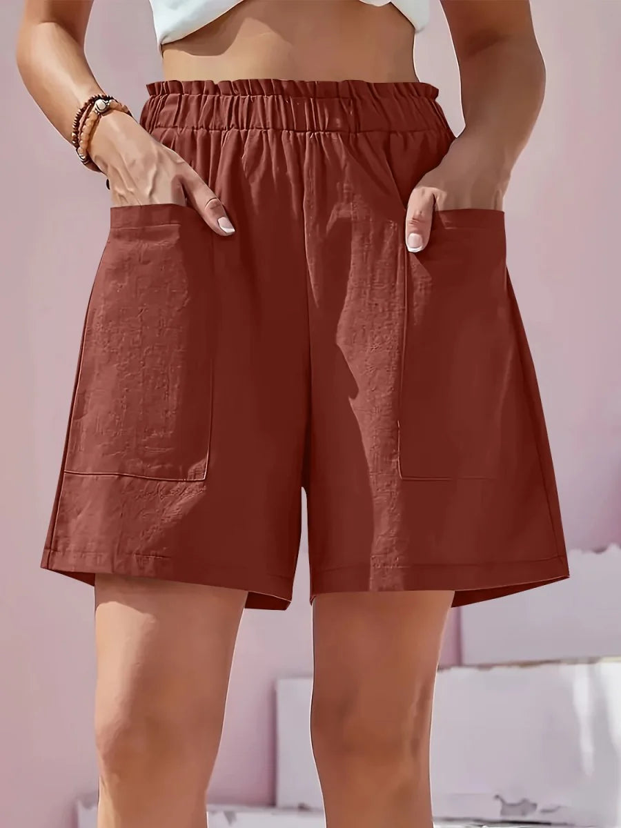 Rust-colored linen-blend shorts with a paperbag waist and large front pockets, shown on a model.