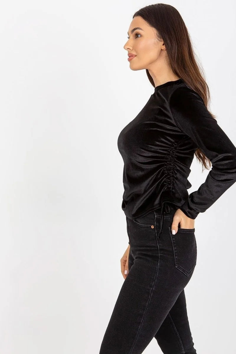 Black velvet long-sleeve top with ruched side detail on model.