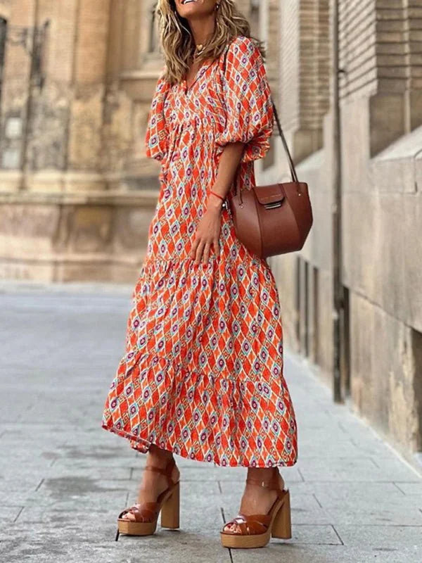 Orange and blue geometric print tiered maxi dress with puff sleeves and brown platform heels.