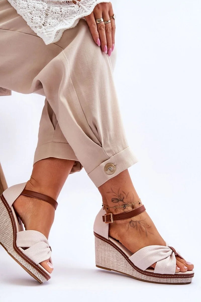 Beige woven wedge sandals with brown ankle straps and knotted toe detail.