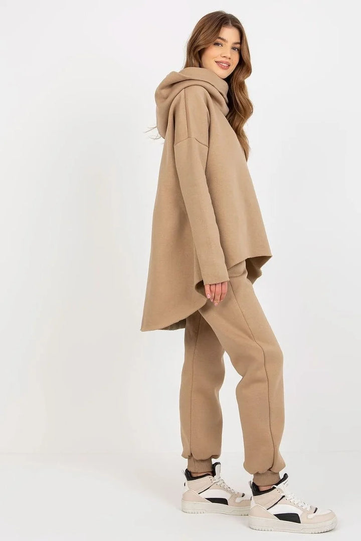 Woman in relaxed fit tan sweatpants and matching oversized hoodie, wearing high-top sneakers.