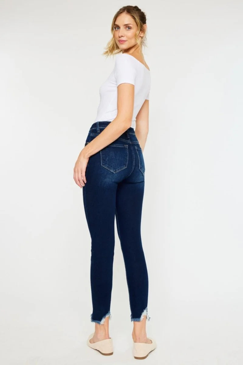 Dark wash, slightly stretchy skinny jeans with frayed hems on a model.