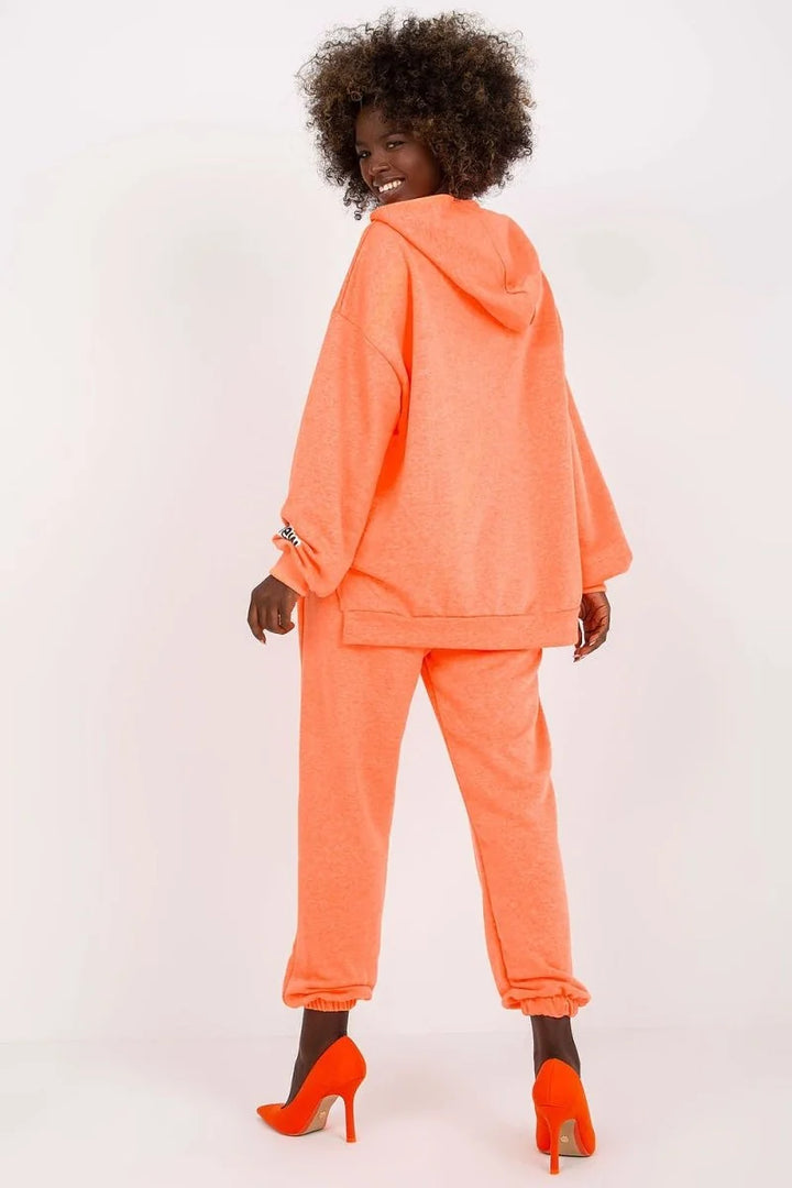 Orange sweatpants with cuffed ankles and a textured knit fabric, paired with vibrant orange high heels.