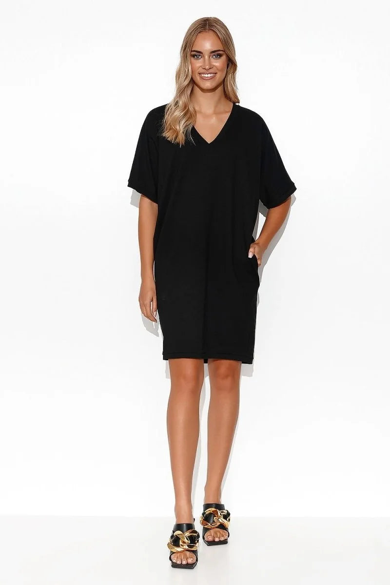 Black V-neck t-shirt dress with pockets, worn by a model with gold chain sandals.