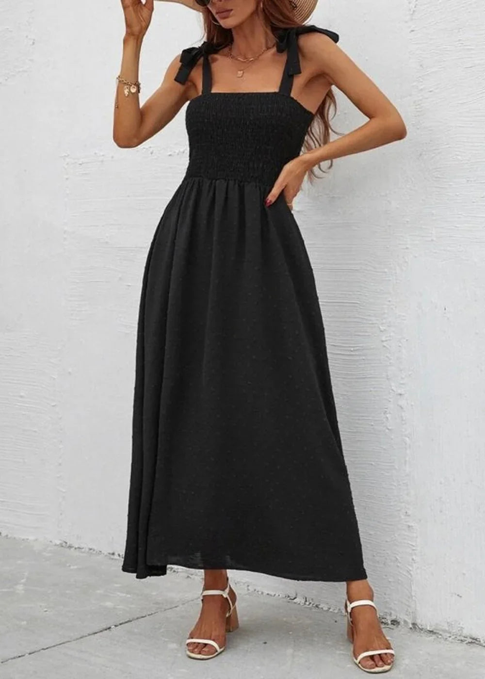 Black smocked maxi dress with tie straps and a subtle dot print, worn on a model.