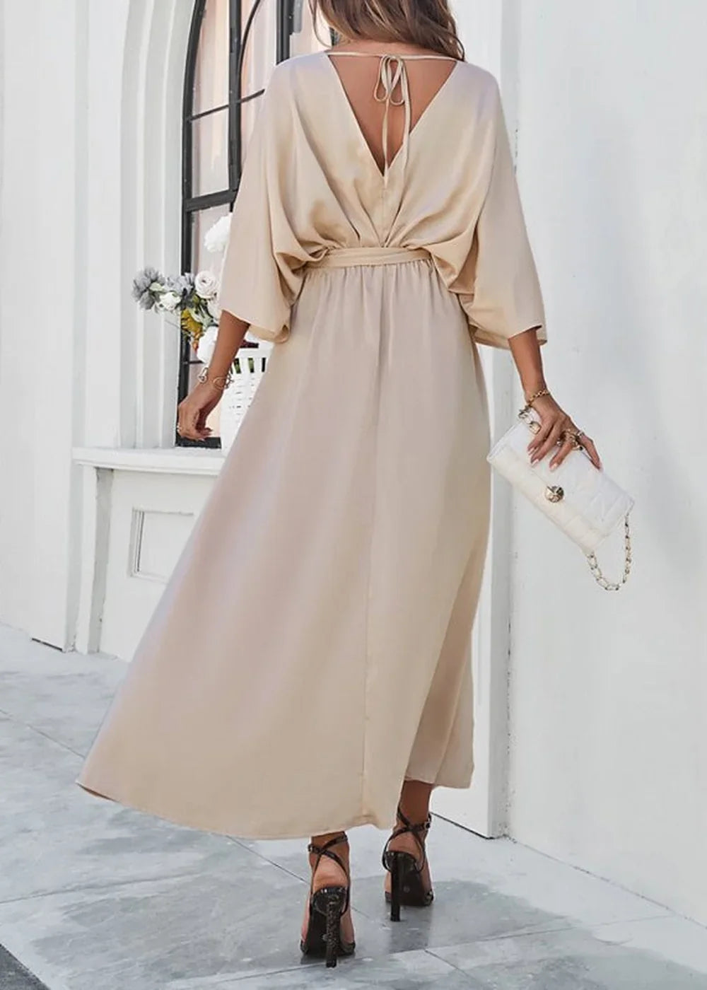 Flowy beige V-neck maxi dress with tie-back detail, cinched waist, and elegant draped sleeves.