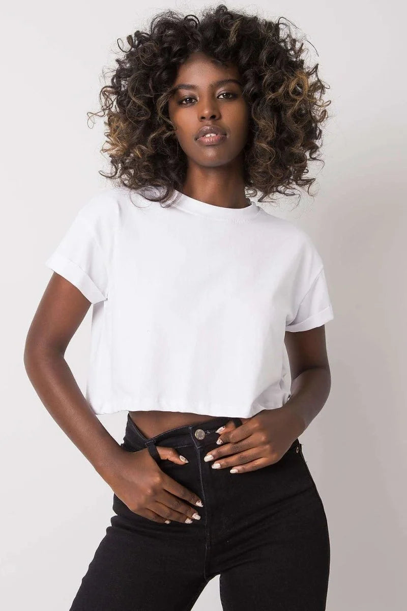 Woman in loose-fit white cropped t-shirt and black jeans with hands in pockets