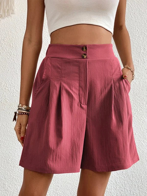Pink textured shorts with double button closure and pleats, on model.