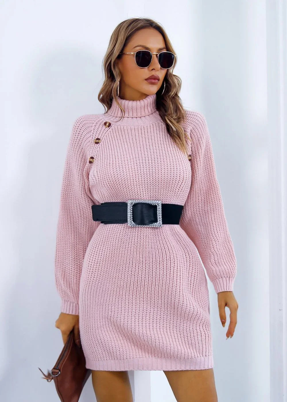 Pink acrylic knit turtleneck sweater dress with a black jeweled belt on a model.