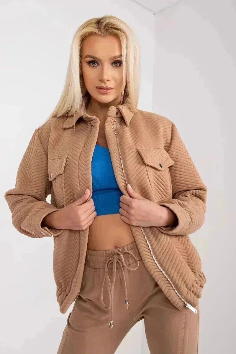 Quilted tan shacket with chevron pattern and zipper closure, worn over a blue crop top.