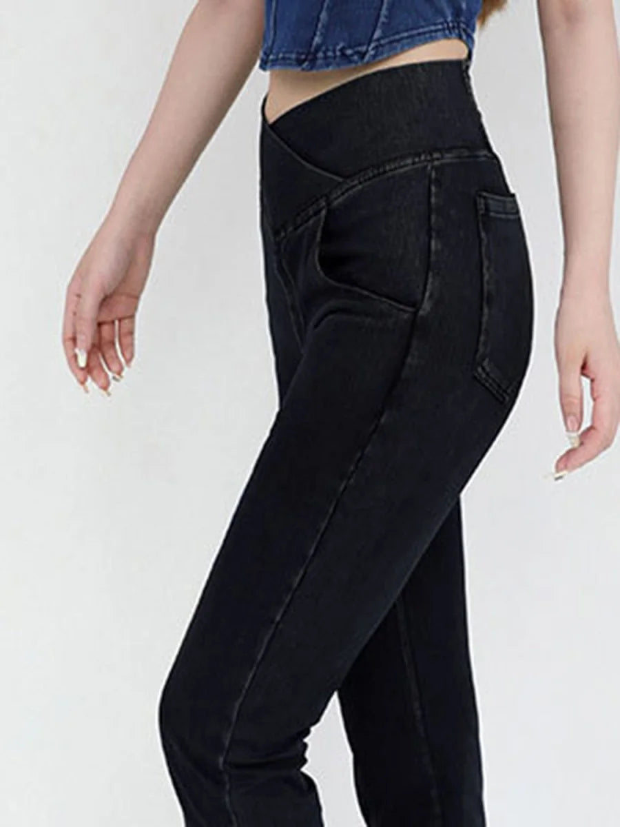 Close-up of dark wash denim jeans with a high, V-shaped waistband on a model.