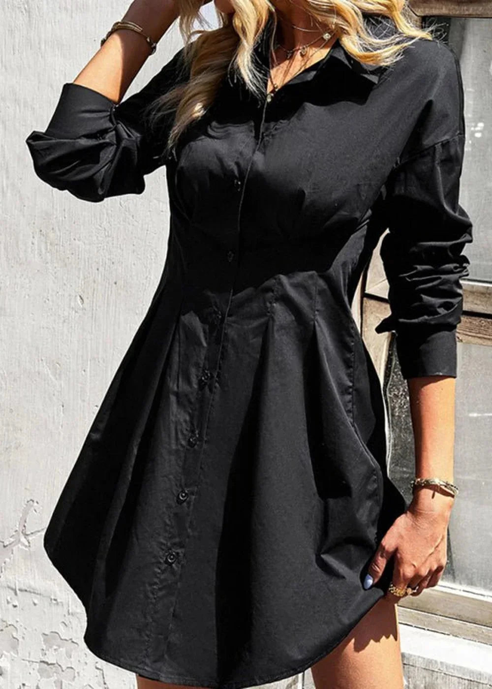 Black cotton shirt dress with button front and pleated skirt, on model.