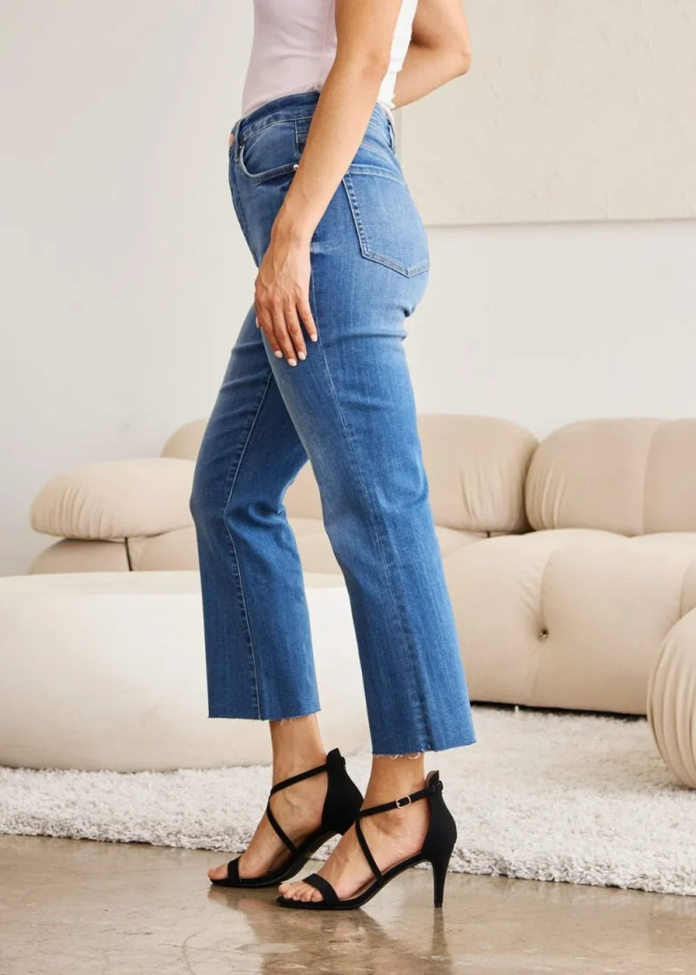 Blue denim flare jeans with a frayed hem, shown on a model wearing black heels.