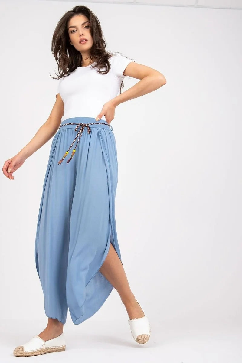 Light blue wide-leg pants with side slits and a braided rope belt with colorful beads on a model.