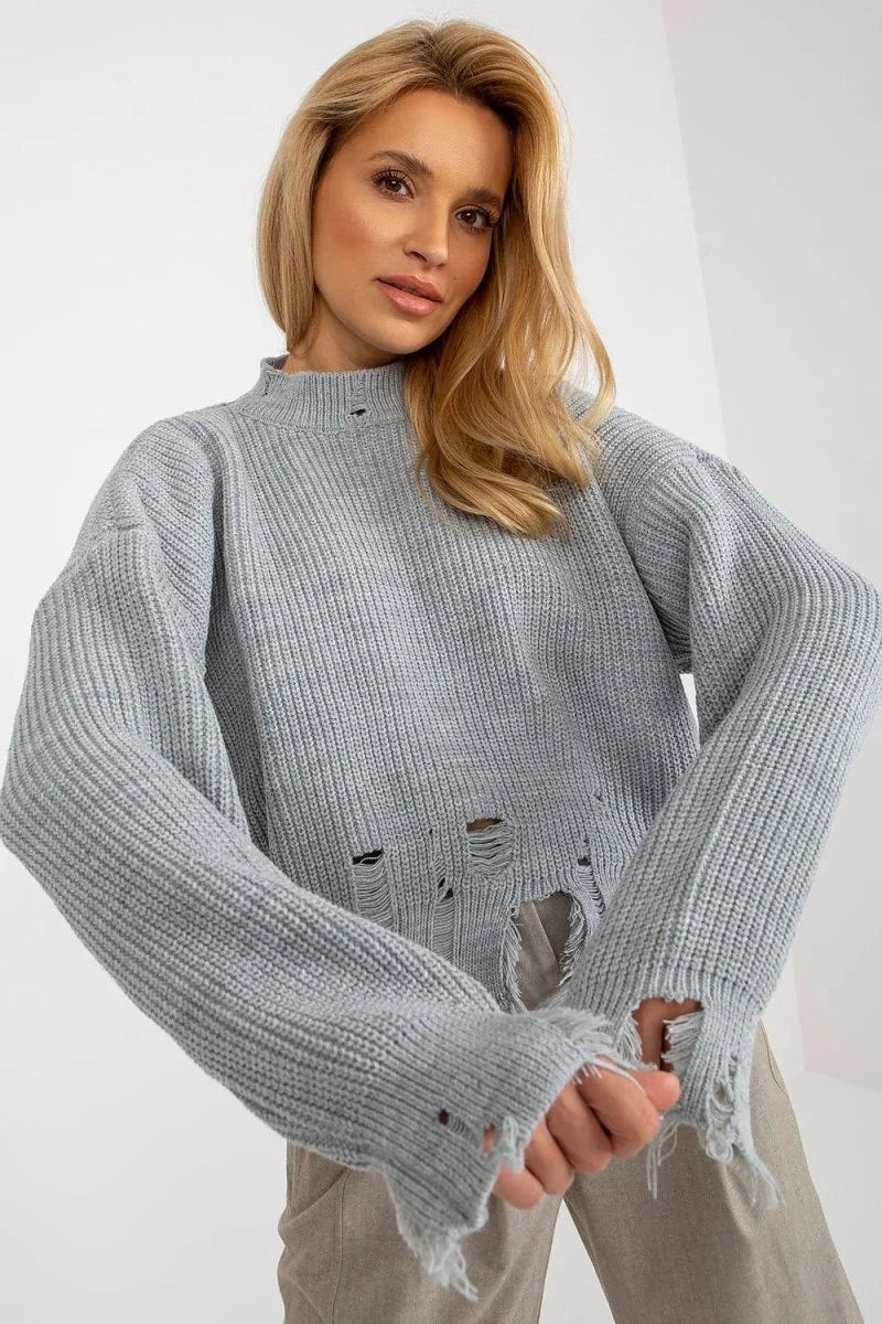Light grey distressed knit sweater with frayed hem and sleeves, on a model.