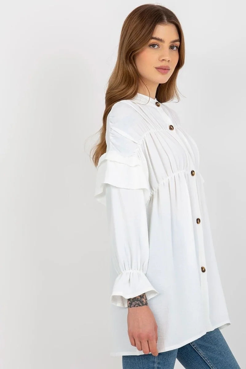 White ruffled blouse with gathered neckline, brown buttons, and flared cuffs on a model.