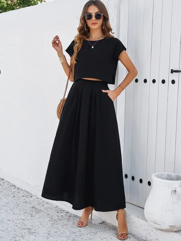 Black two-piece set with a cropped top and a full, pleated midi skirt on a model.