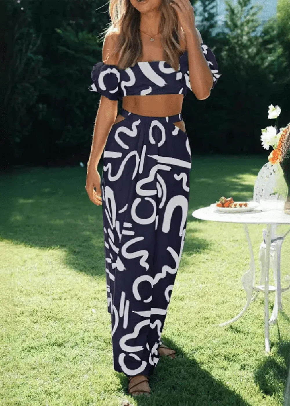 Navy blue and white abstract print off-the-shoulder crop top and cutout maxi skirt set on model.