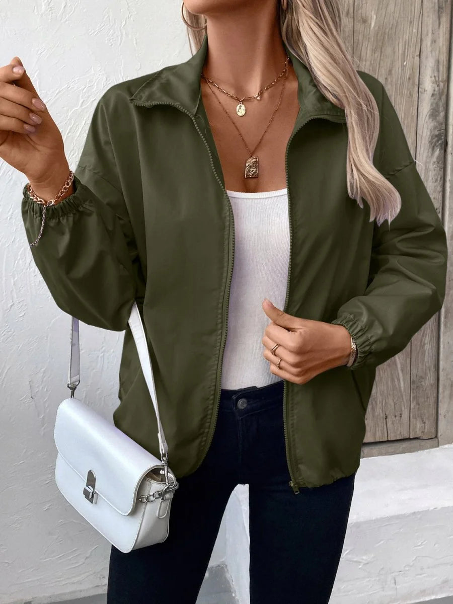 Olive green bomber jacket with a zip-up front, elastic cuffs, and a white crossbody bag.