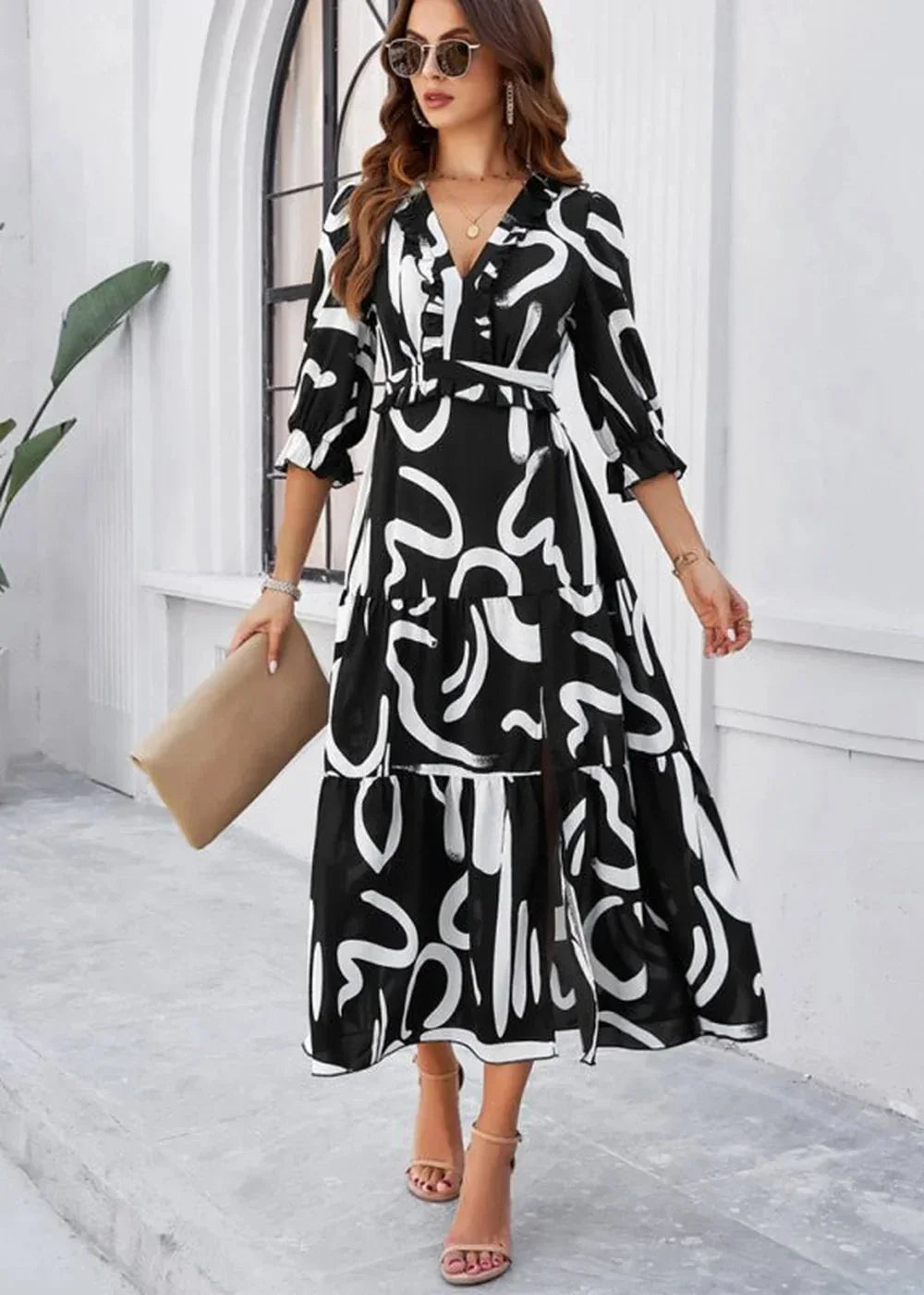 Black and white abstract print midi dress with ruffled V-neck and tiered skirt, worn by a model holding a clutch.