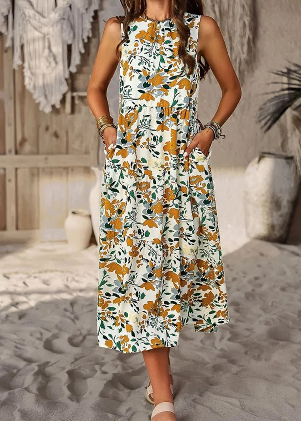 A sleeveless white dress with a yellow and green floral print, featuring pockets and a tiered skirt, worn by a model.