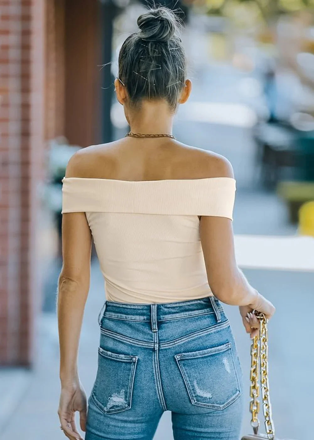 Off-the-shoulder cream ribbed top with distressed denim jeans, showing the back view.