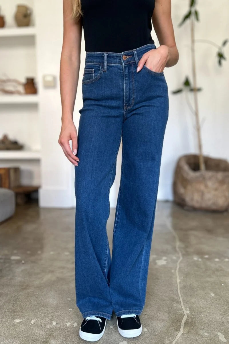 Full-length shot of dark wash, wide-leg jeans with a regular fit, worn by a model with black sneakers.