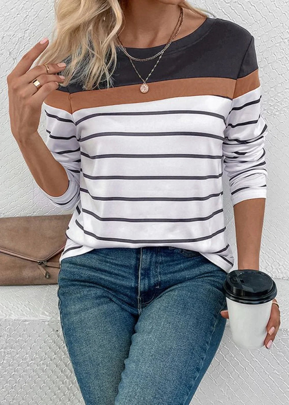 Woman in a striped long-sleeve shirt with black, brown, and white bands, paired with blue jeans.